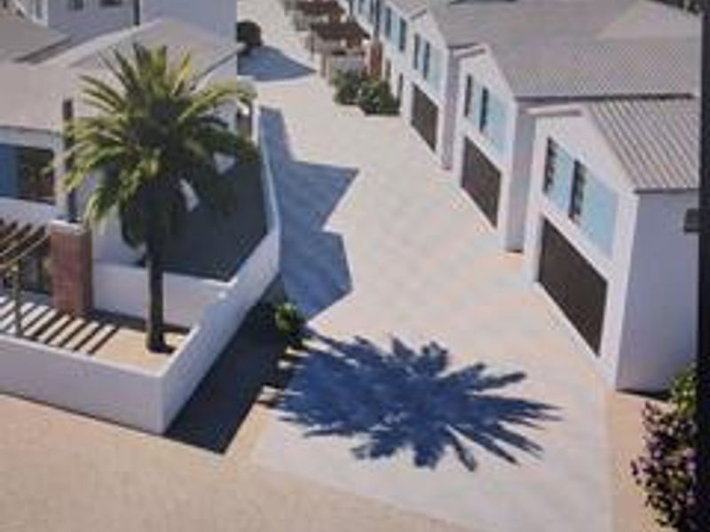An aerial perspective of a townhouse development featuring multiple units with paved driveways and garage access.