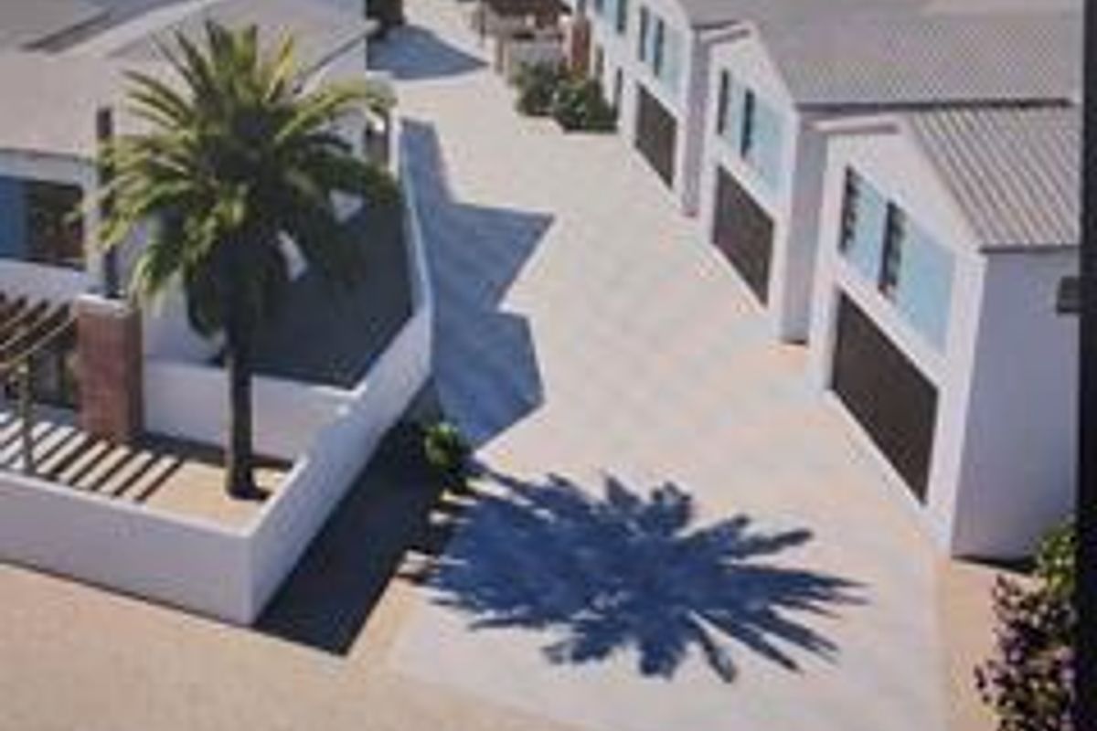 An aerial perspective of a townhouse development featuring multiple units with paved driveways and garage access.