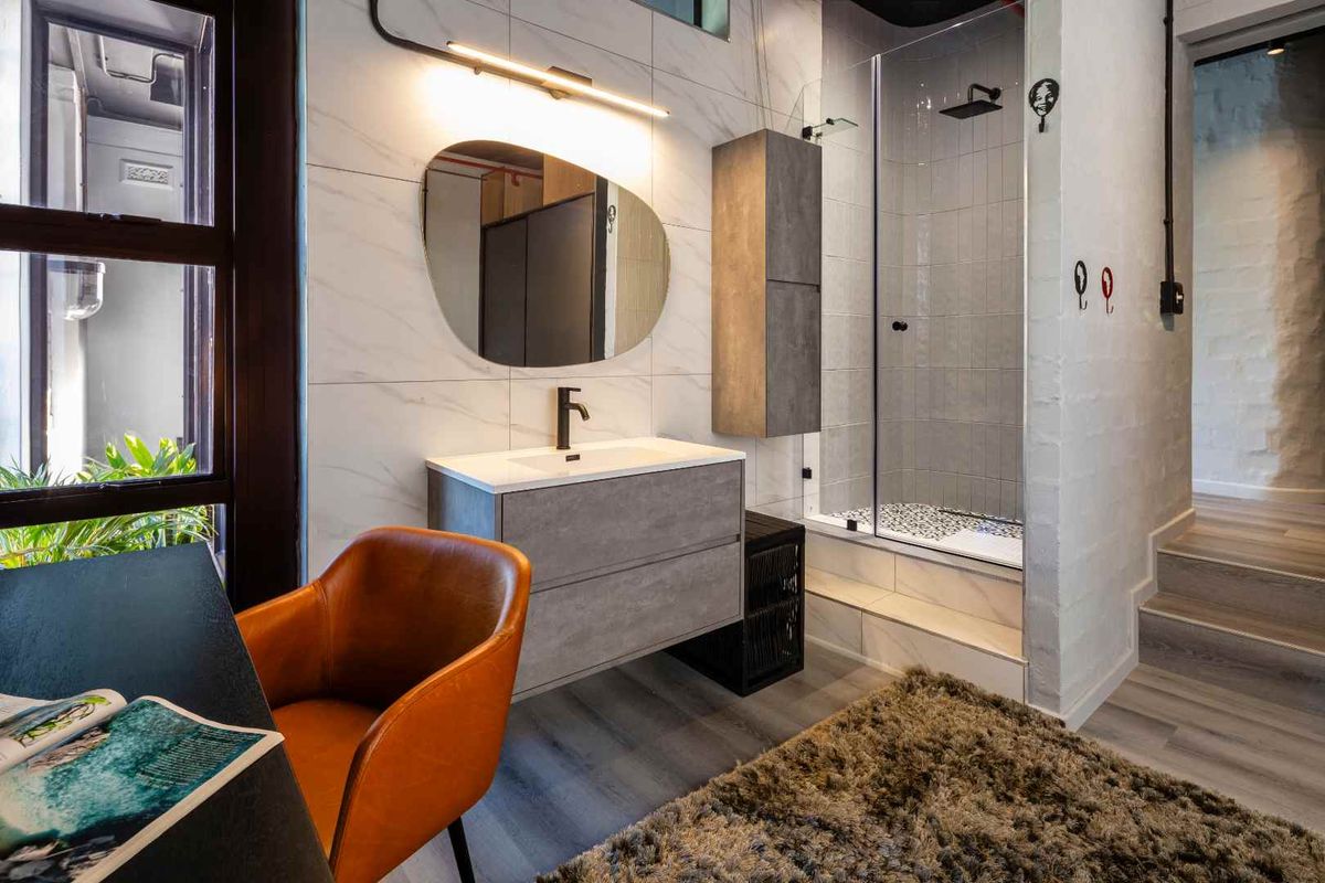 Modern bathroom featuring a floating vanity, integrated sink, wall-mounted faucet, and a glass-enclosed shower with contemporary tiled finishes.
