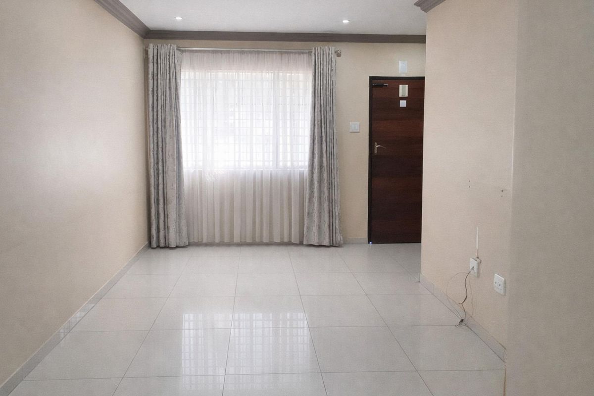 A bright, empty living room featuring neutral tiled flooring, modern cornicing, and a timber entrance door.