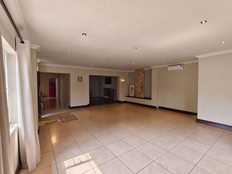 Spacious, open-plan living area featuring neutral tiled flooring, recessed lighting, a split-system air conditioner, and a decorative stone-clad feature wall.