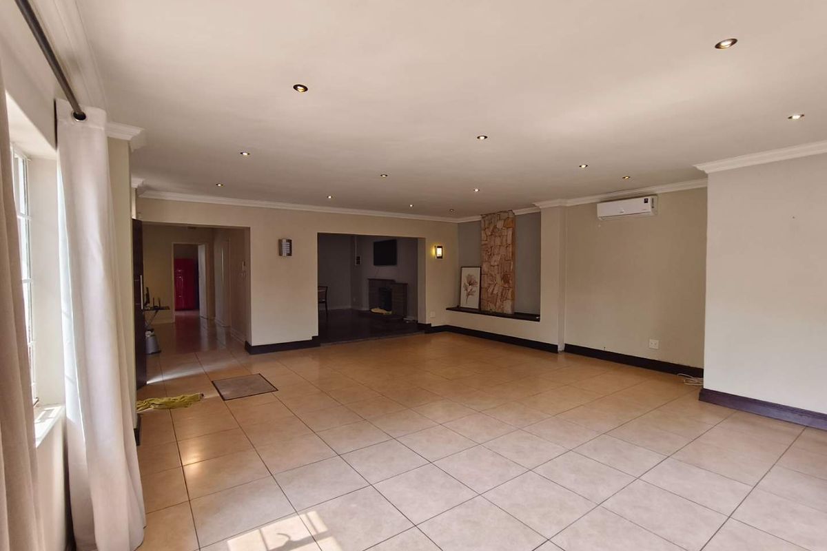 Spacious, open-plan living area featuring neutral tiled flooring, recessed lighting, a split-system air conditioner, and a decorative stone-clad feature wall.