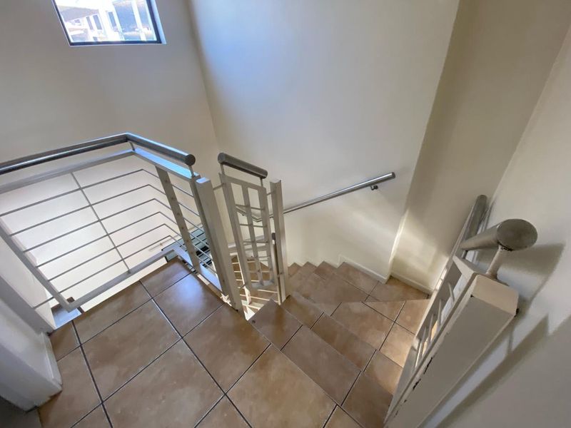 A functional staircase featuring tiled steps and a secure metal balustrade with a wall-mounted handrail.