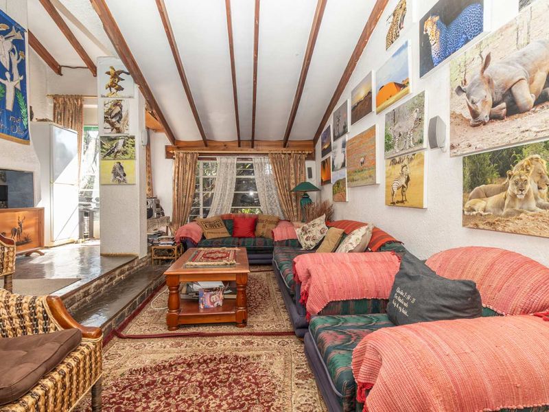 Spacious living room featuring exposed timber ceiling beams, a built-in fireplace, and tiled flooring, offering a rustic and cozy atmosphere.