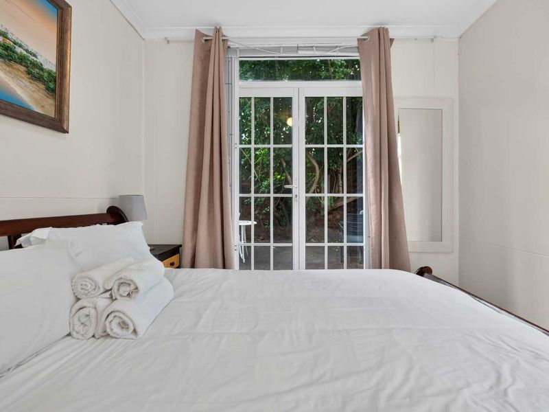 A well-maintained bedroom featuring classic french doors that provide direct access to the outdoor area, allowing for natural light and ventilation.
