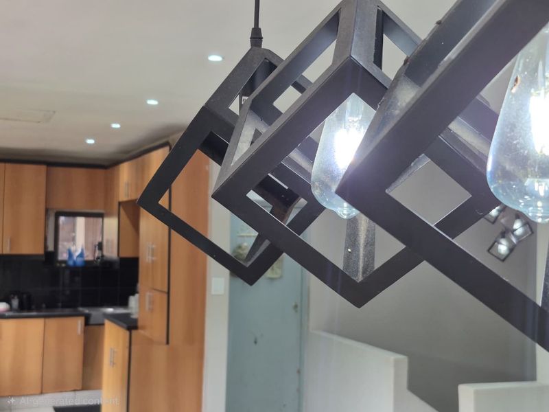 A close-up view of modern geometric pendant lighting in a kitchen featuring wooden cabinetry and dark countertops.