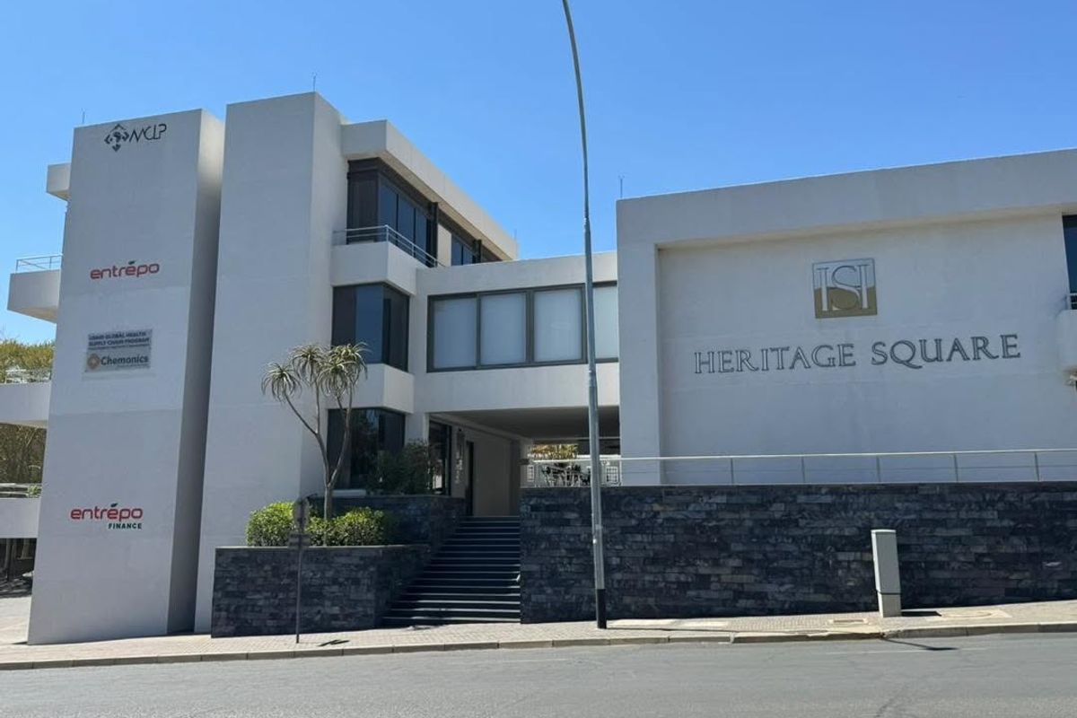 Modern multi-story office building facade featuring stone cladding, glass windows, and prominent signage for Heritage Square.
