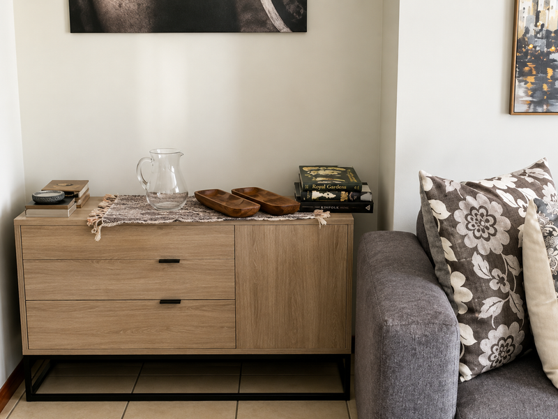 A view of a living room corner featuring a modern wooden sideboard and a portion of a grey sofa.