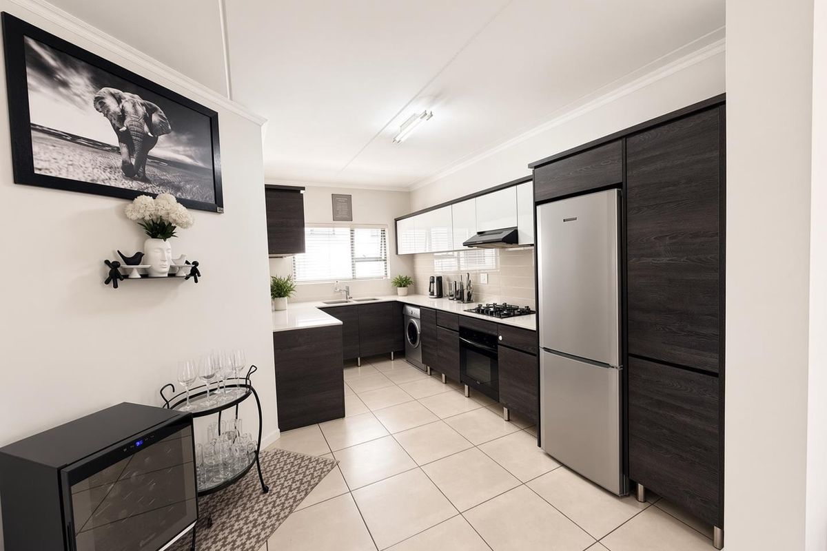 Modern kitchen featuring dark wood cabinetry, light countertops, gas hob, built-in oven, extractor fan, and tiled flooring in an open-plan layout.