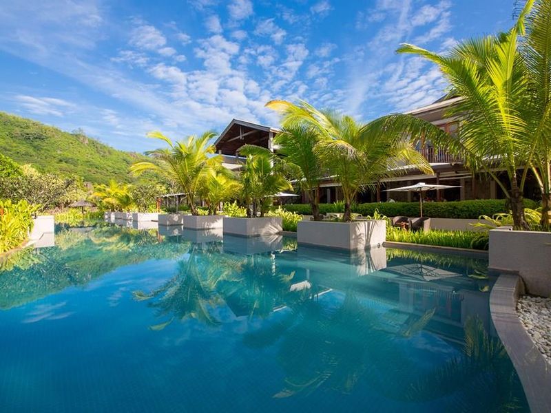 A beautifully landscaped swimming pool area featuring integrated planters and lush tropical greenery, set against the backdrop of the villa architecture.