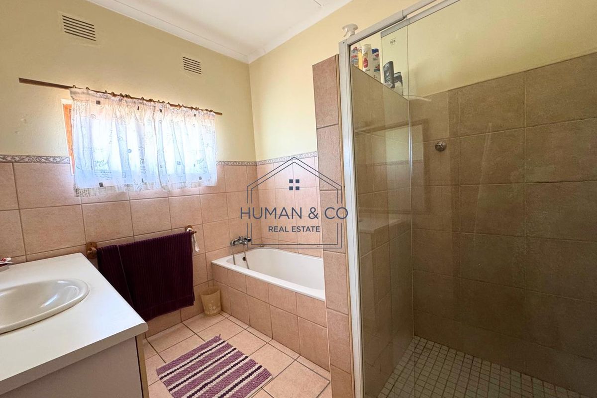 A functional bathroom featuring a built-in bathtub, a separate glass-enclosed shower, and a vanity basin with tiled walls and flooring.