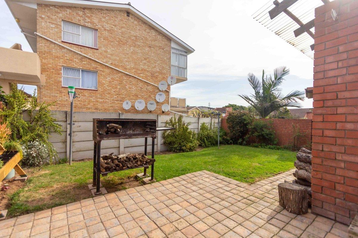 A private rear garden featuring a paved patio area, brick boundary walls, and a pergola structure, providing a functional outdoor space for the townhouse.