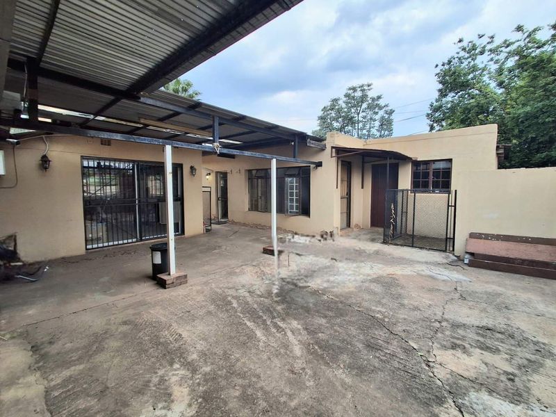 Rear exterior view featuring a covered patio area with concrete paving, security gates, and sliding door access to the main dwelling.