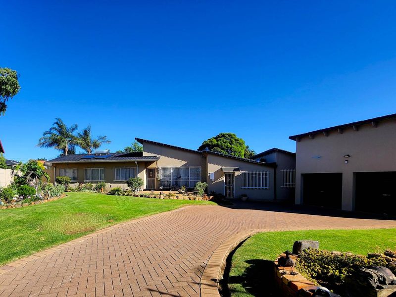 A well-maintained single-story residence featuring a paved driveway, double garage, solar geyser, and established garden with security bars on windows.