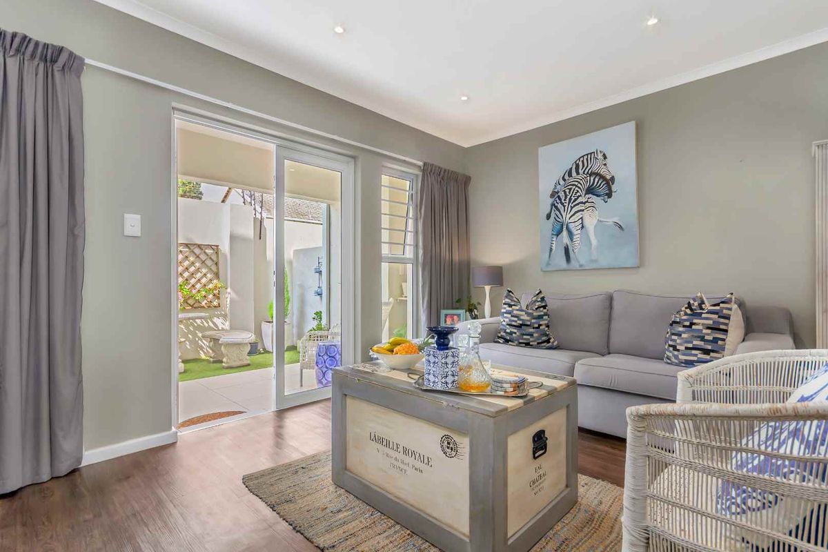 A bright living room featuring laminate flooring, recessed ceiling lighting, and sliding glass doors providing direct access to a private patio area.