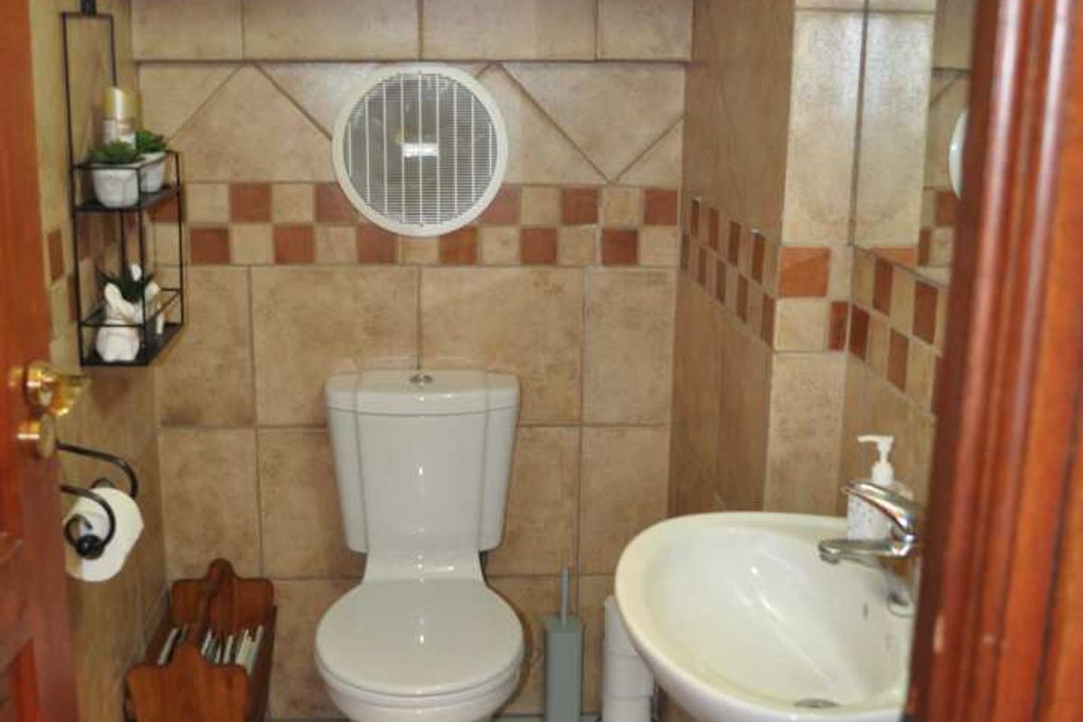 A compact guest bathroom featuring a pedestal basin, toilet, and neutral wall and floor tiling.