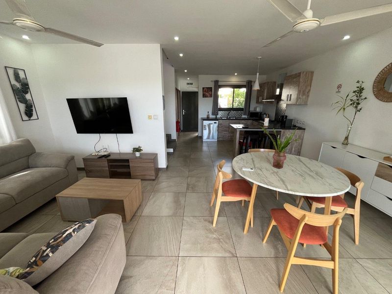 An open-plan living, dining, and kitchen area featuring modern tiled flooring, recessed lighting, ceiling fans, and a functional kitchen with integrated appliances.