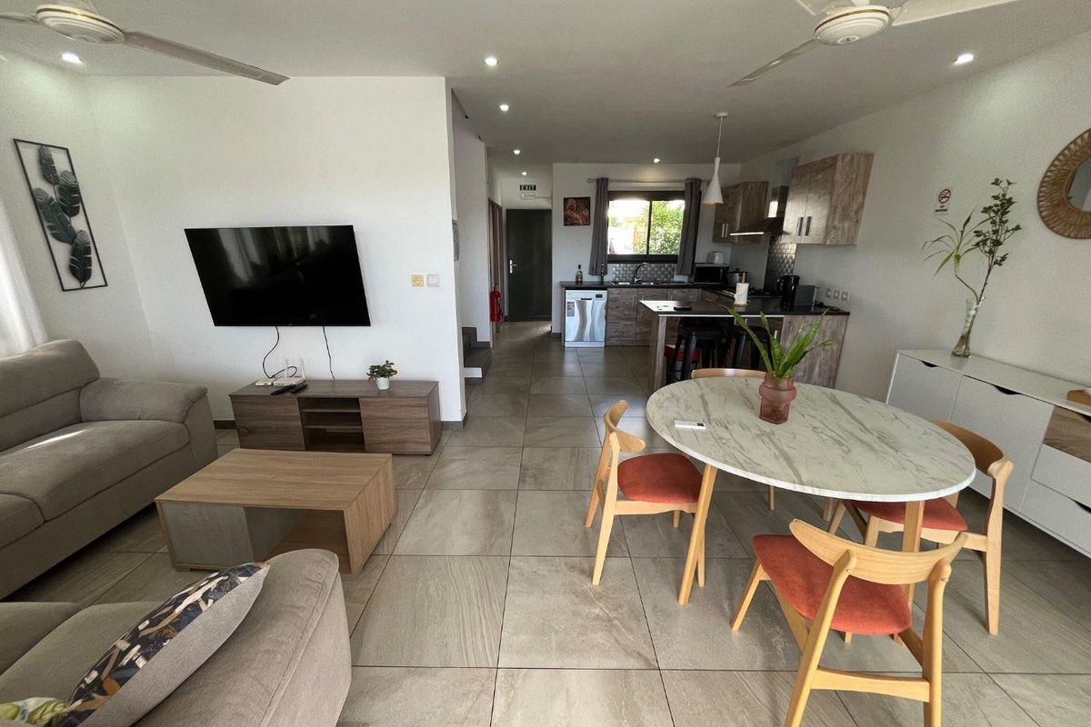 An open-plan living, dining, and kitchen area featuring modern tiled flooring, recessed lighting, ceiling fans, and a functional kitchen with integrated appliances.