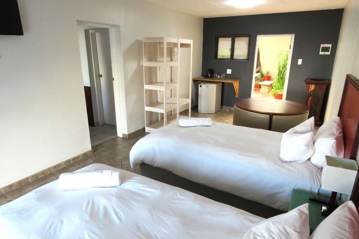 A guest bedroom featuring twin beds, tiled flooring, and direct access to an outdoor patio area.