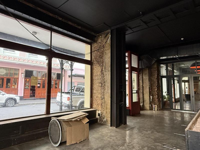 Spacious open-plan retail unit featuring large display windows, exposed brickwork, industrial steel columns, and high ceilings with exposed ducting.
