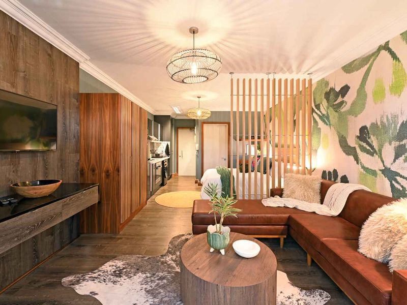 A modern open-plan apartment featuring wood-look flooring, a timber slat room divider, and stylish feature wall paneling, creating a cohesive and contemporary living space.