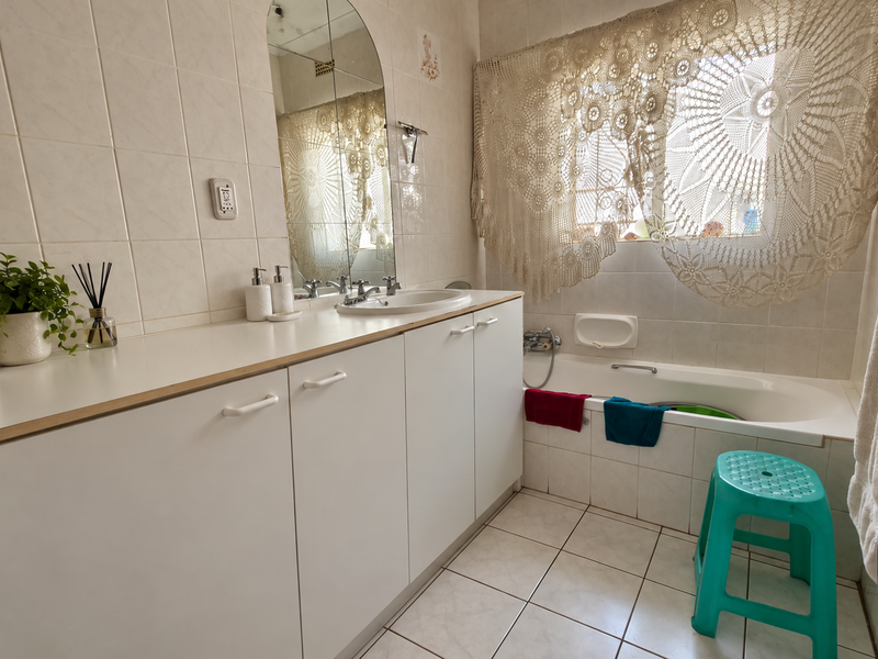 A functional bathroom featuring a built-in vanity with basin, tiled walls and flooring, and a standard bathtub.