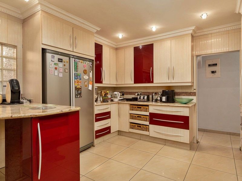 A well-maintained kitchen featuring two-tone cabinetry, granite countertops, tiled flooring, and recessed lighting, offering a functional and organized culinary space.