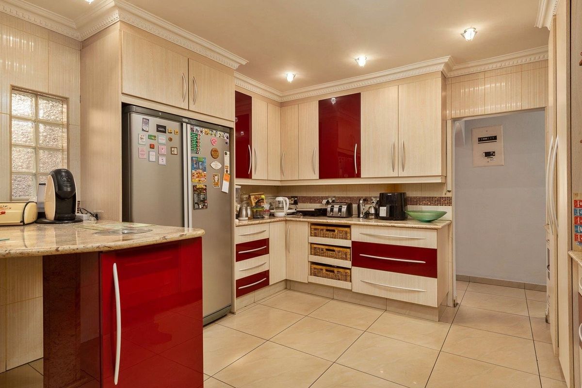 A well-maintained kitchen featuring two-tone cabinetry, granite countertops, tiled flooring, and recessed lighting, offering a functional and organized culinary space.
