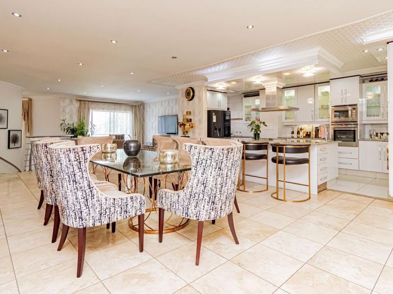 Spacious open-plan living and dining area featuring tiled floors, recessed lighting, and a modern kitchen with integrated appliances and a central island.