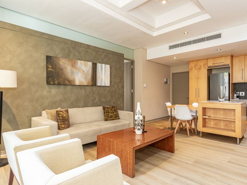 Modern open-plan living area featuring a well-appointed kitchen with timber cabinetry, integrated appliances, and a spacious lounge area with recessed ceiling details.