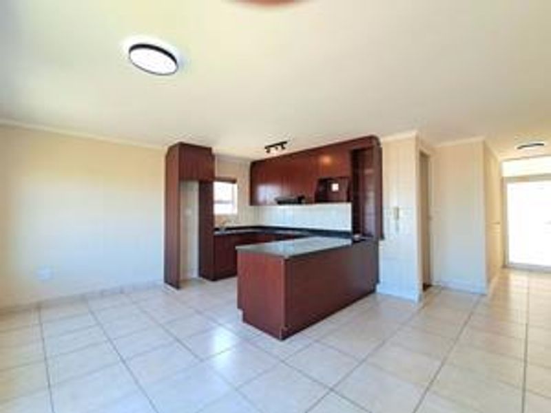 Open plan living area featuring a kitchen with dark wood cabinetry, laminate countertops, and tiled flooring throughout.