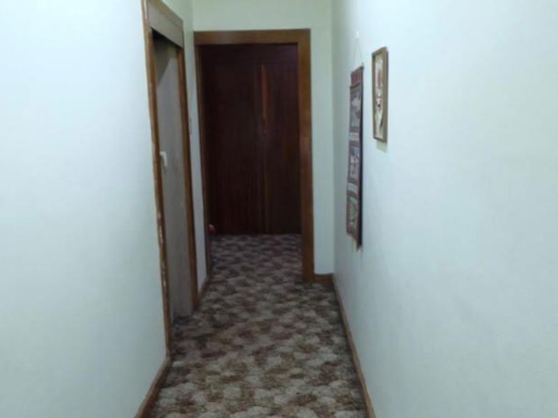 A narrow residential hallway featuring carpet flooring and wooden door frames leading to adjacent rooms.