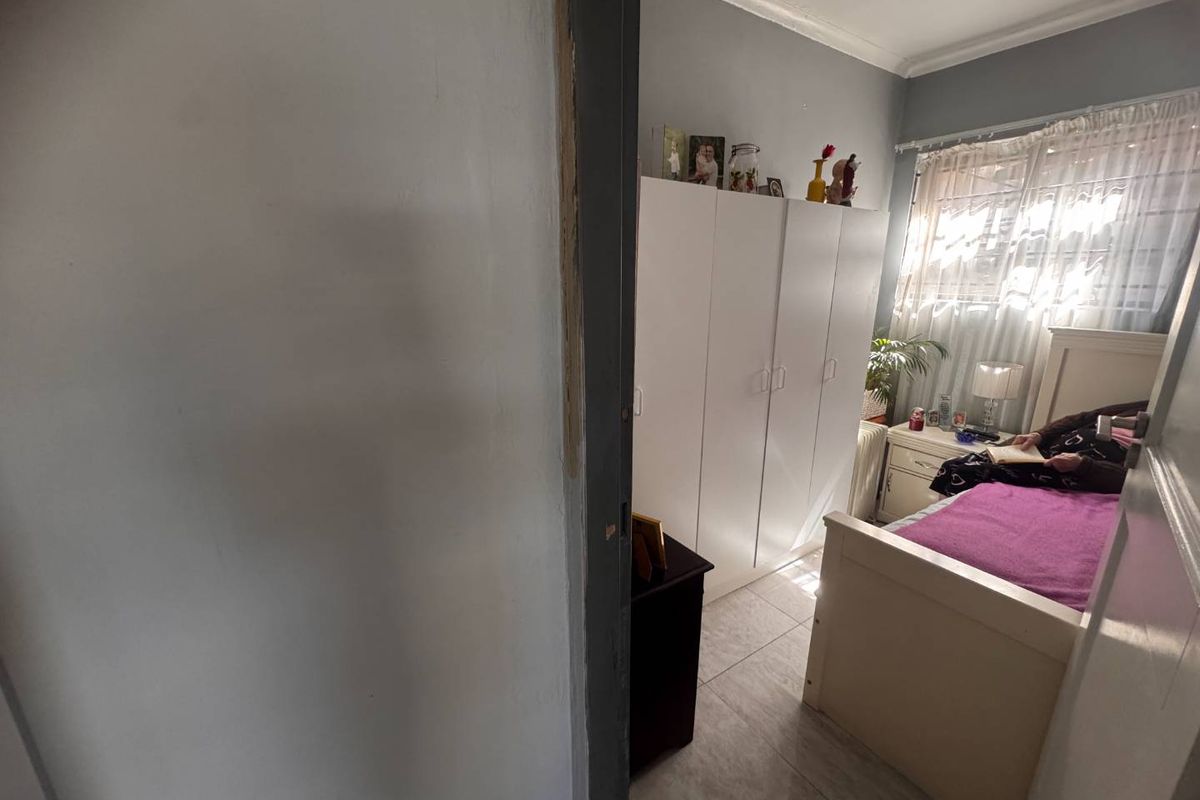 A bedroom featuring tiled flooring, a built-in wardrobe, and a window with natural light.