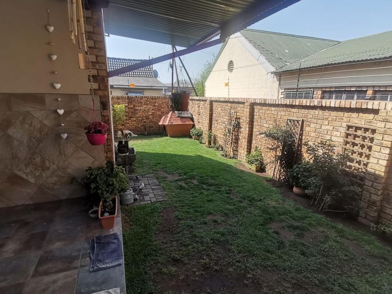 A covered patio area overlooking a private garden with brick boundary walls and tiled flooring.