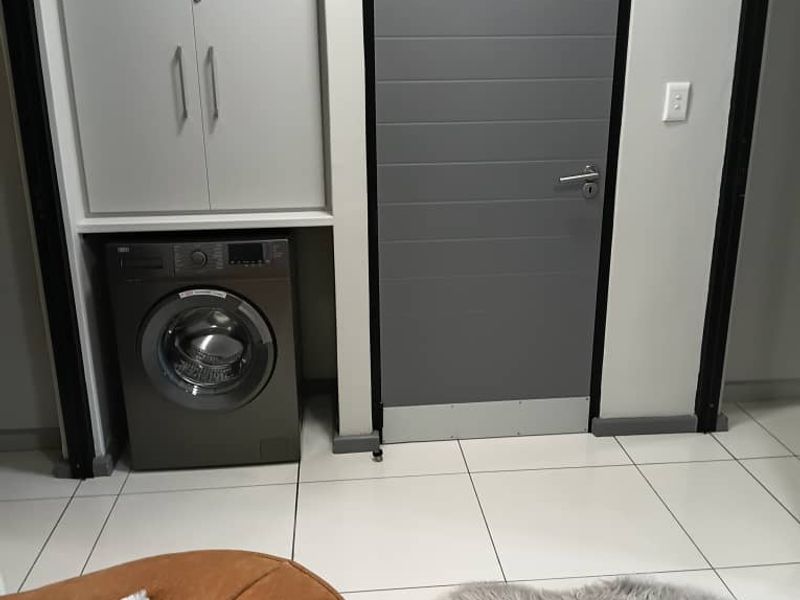 A functional laundry area featuring built-in cabinetry for storage and tiled flooring, integrated into the apartment layout.