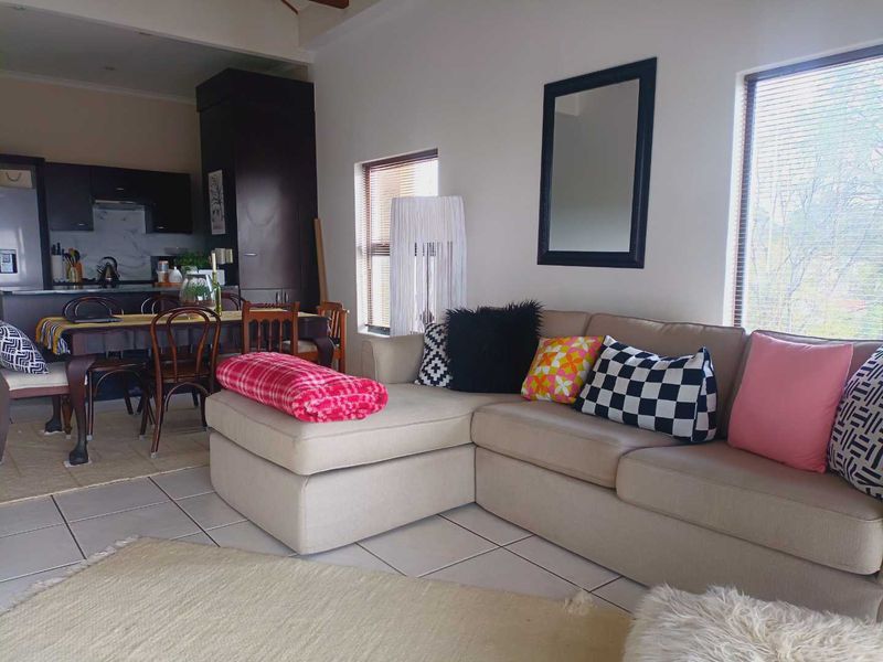 Open-plan living and dining area featuring tiled flooring, neutral walls, and an integrated kitchen with dark cabinetry.
