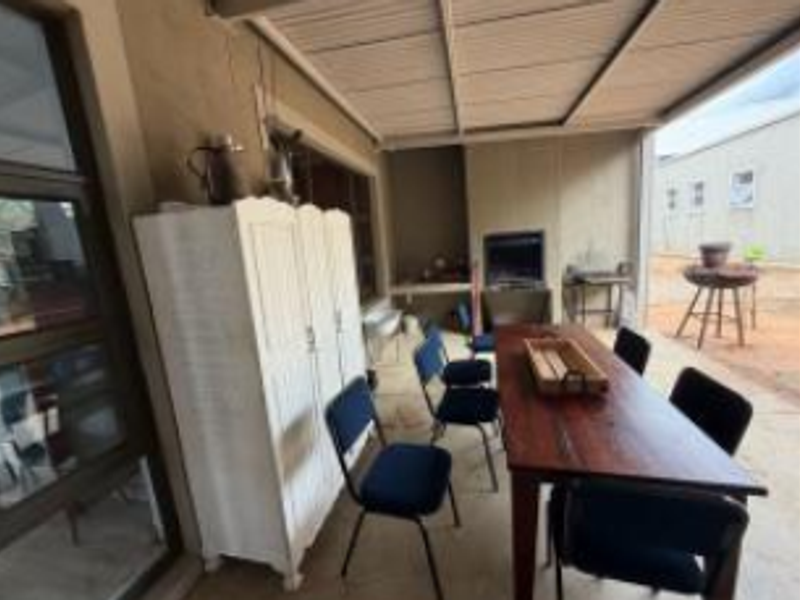 A covered outdoor patio area featuring a built-in braai and direct access to the home through sliding doors.