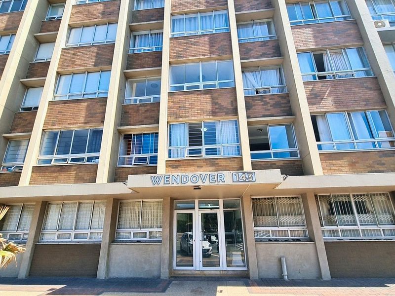 Front elevation of Wendover 143 apartment building, featuring a multi-story brick facade with aluminum windows and a central glass entrance.