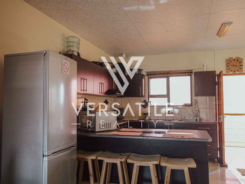 A functional kitchen featuring dark wood cabinetry, laminate countertops, and a tiled backsplash, providing a practical layout for daily meal preparation.