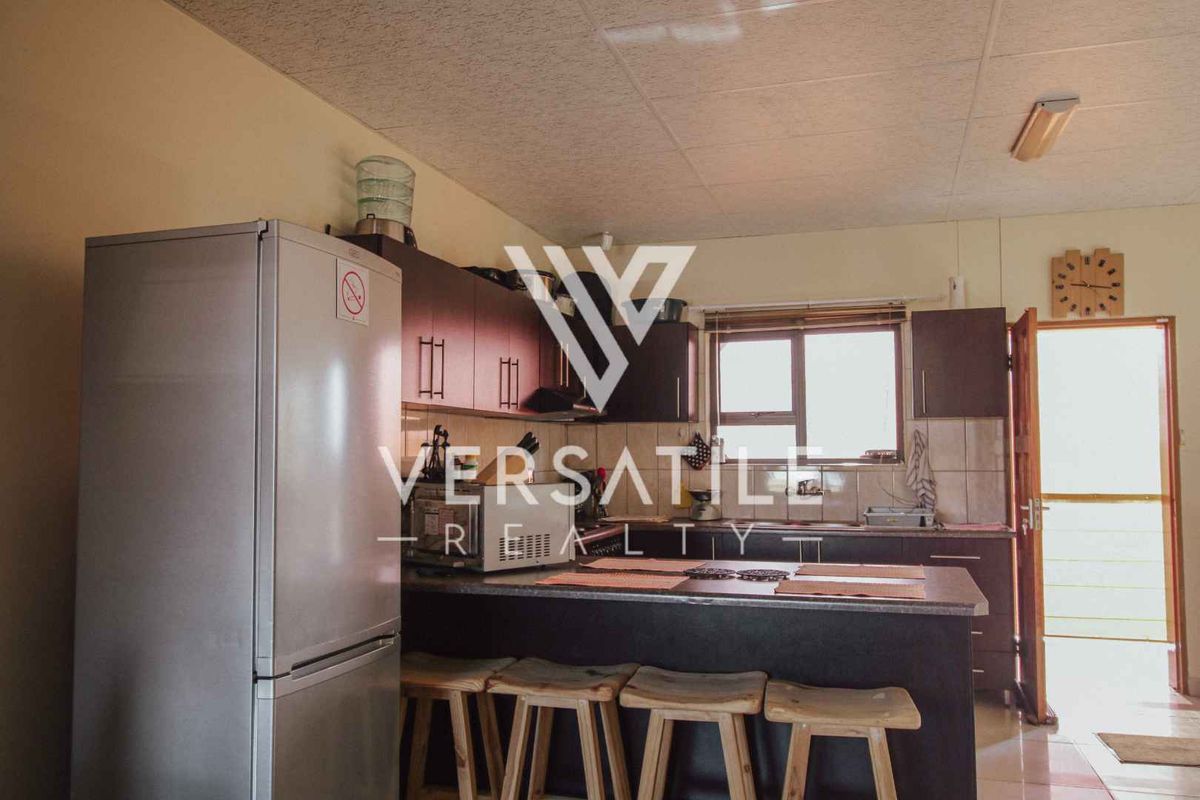 A functional kitchen featuring dark wood cabinetry, laminate countertops, and a tiled backsplash, providing a practical layout for daily meal preparation.