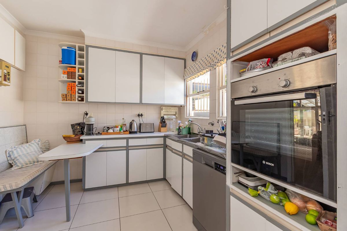 A functional kitchen featuring built-in cabinetry, a double sink, integrated dishwasher, and a built-in oven, with tiled flooring and backsplash throughout.
