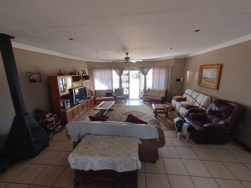 Spacious living room featuring tiled flooring, a freestanding fireplace, and a ceiling fan, with direct access to the outdoor area through sliding glass doors.