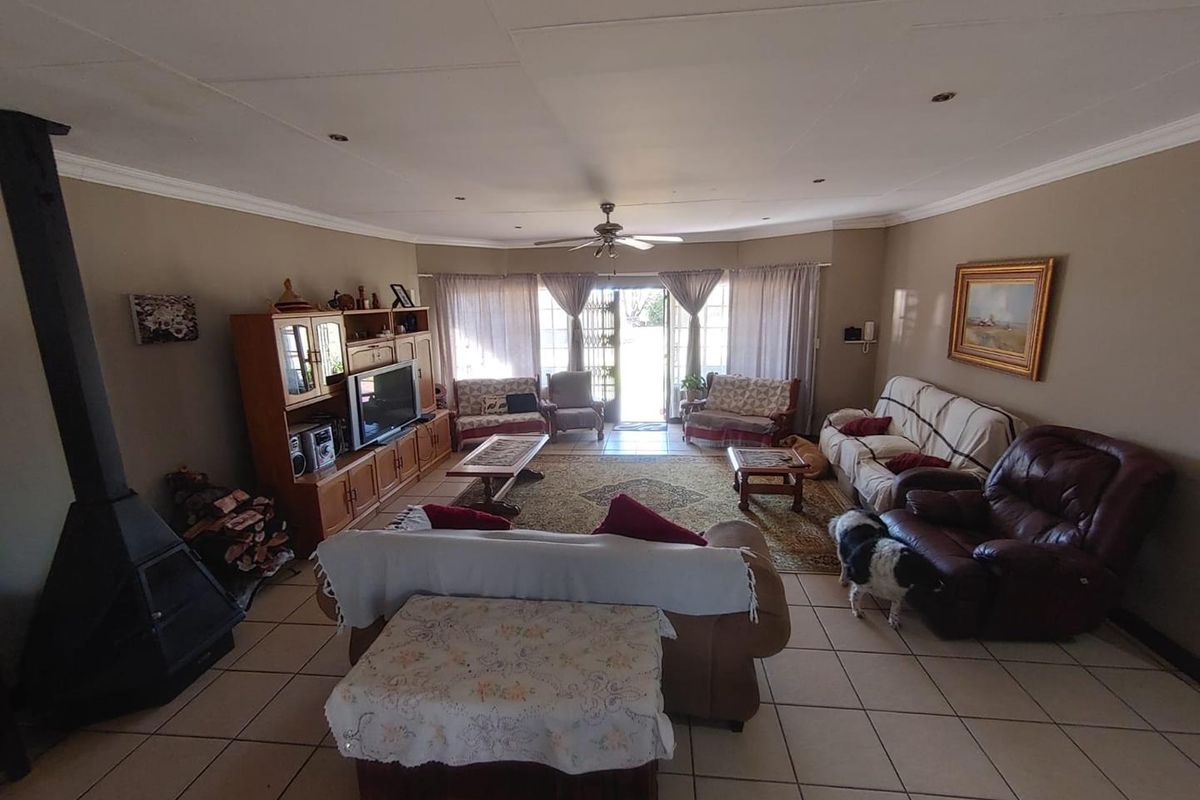 Spacious living room featuring tiled flooring, a freestanding fireplace, and a ceiling fan, with direct access to the outdoor area through sliding glass doors.