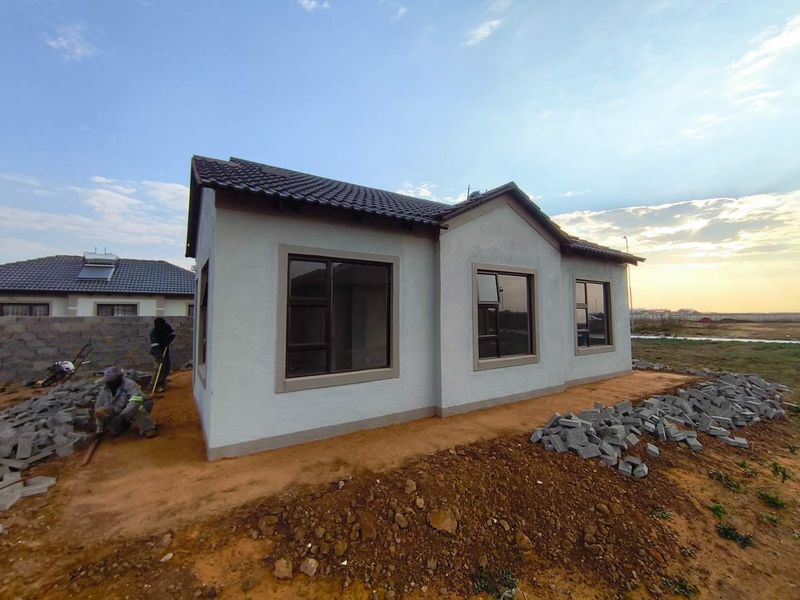 A newly constructed single-story house featuring a tiled roof and modern aluminium window frames, currently undergoing final exterior landscaping and site finishing.