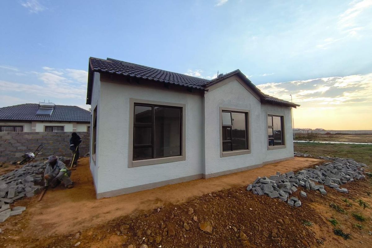 A newly constructed single-story house featuring a tiled roof and modern aluminium window frames, currently undergoing final exterior landscaping and site finishing.