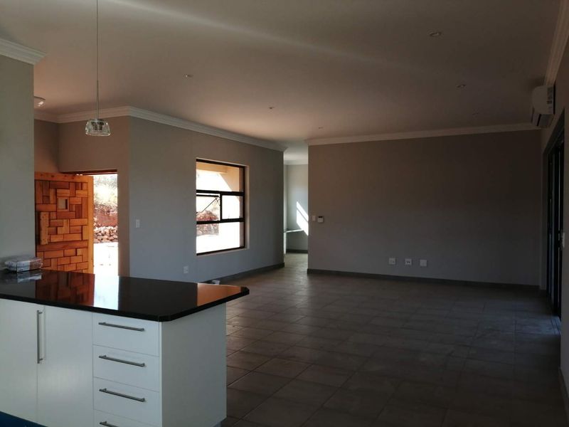 Spacious open-plan living area featuring a modern kitchen island with granite countertops, tiled flooring, and neutral wall finishes, offering a bright and versatile layout.