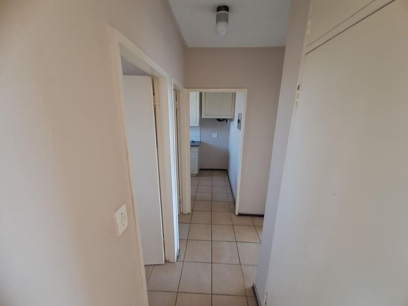 A functional hallway with tiled flooring and built-in storage, providing access to adjacent rooms and a view into the kitchen area.