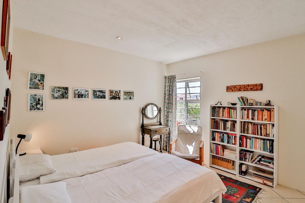 A well-lit bedroom featuring neutral walls, tiled flooring, and a window providing natural light.