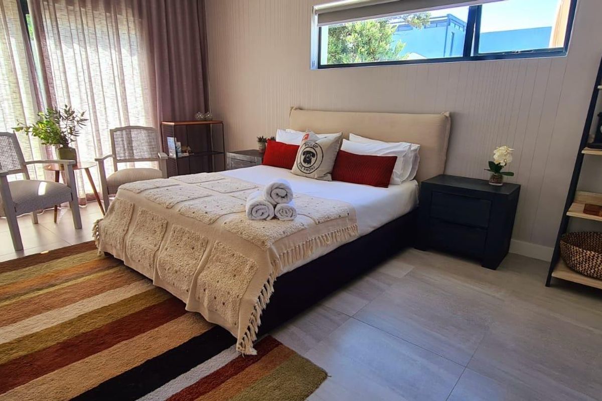 A well-maintained bedroom featuring large sliding glass doors, neutral wall paneling, and modern tiled flooring with ample natural light.
