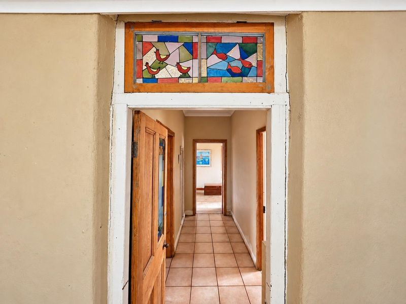 A hallway featuring tiled flooring, wooden door frames, and a decorative stained glass transom window above the entrance.